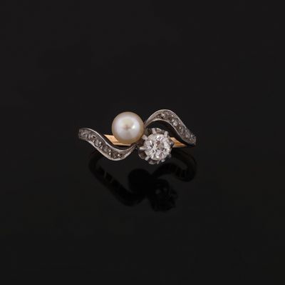 a pearl and diamond ring on a black surface