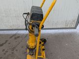 a close up of a yellow machine on the ground near a building