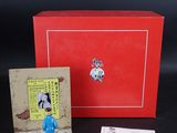 une petite figurine représentant un homme en costume bleu, à côté d'une boîte rouge
