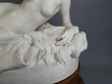 une statue blanche représentant une femme allongée sur un lit