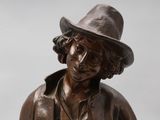 a bronze statue of a man with a hat on