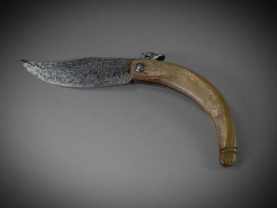 a close up of a knife with a wooden handle on a gray surface