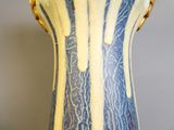 un vase bleu et blanc orné d'une bande jaune