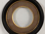 black and gold framed picture of a round mirror on a white wall