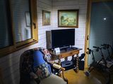 a television in the corner of a room with a chair and a bike
