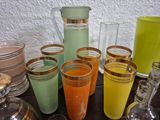 many different colored glasses and pitchers on the table