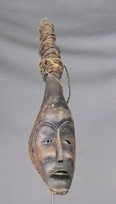 Masque en bois à patine sombre figurant un visage ovale étir…