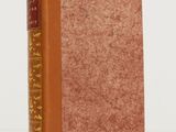 un vieux livre à la couverture marron posé sur une table blanche