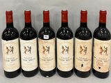 six bouteilles de vin sont alignées sur une table