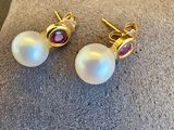une paire de boucles d'oreilles en perles et rubis posée sur un coussin
