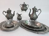 a silver plate with a tea pot and a plate with a bowl on it