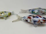 three glass fish figurines sitting next to each other on a white surface