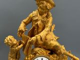 a gold clock with a man and a child sitting on top of it