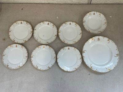 six assiettes blanches bordées d'or sont disposées sur une table