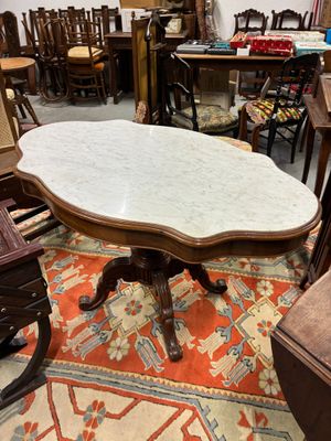 une table au plateau en marbre dans une pièce remplie de meubles anciens