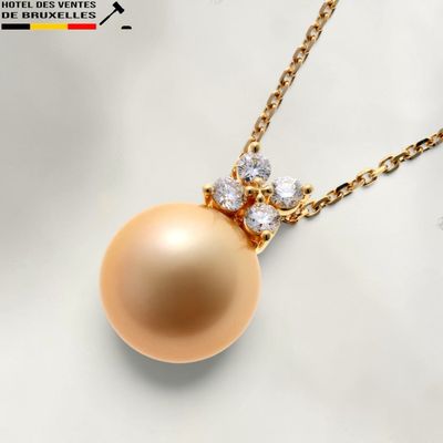 une photo d'un pendentif en or orné d'une perle dorée et de diamants, suspendu à une chaîne en or