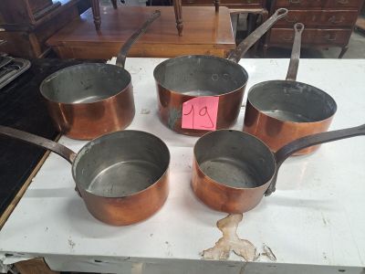 plusieurs casseroles et poêles posées sur une table, avec une étiquette de prix