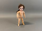 a wooden doll that is standing on a gray surface