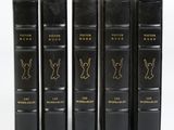 quatre livres noirs sont alignés sur une surface blanche