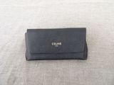 a black celine wallet on a bed with a white background