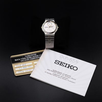 a close up of a watch on a table next to a booklet