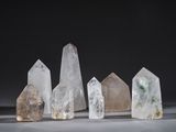 a group of five different sized quartz crystals on a white surface