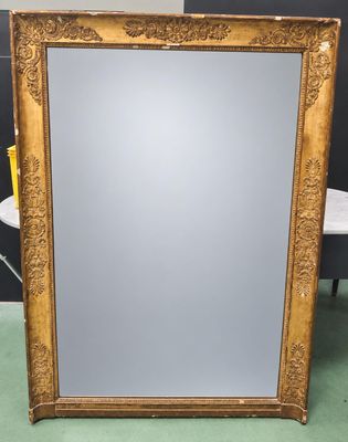 a large gold framed mirror with ornate design on a green floor