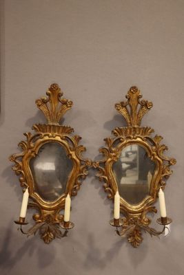 deux miroirs dorés fixés au mur, dans lesquels sont disposées des bougies