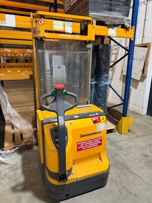 a forklift in a warehouse with pallets in the background
