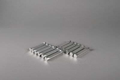 four pieces of silver metal are arranged on a white surface