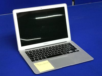 un ordinateur portable posé sur une table, sur lequel est collé un post-it
