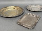 three silver plates and a silver tray on a table