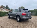 a grey porsche cayen is parked in a gravel lot