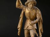 une statue antique en bronze représentant un homme tenant une lance et un chien