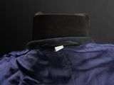 a close up of a blue jacket with a black hat on a mannequin