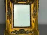 an ornate gold frame with a mirror on top of a table