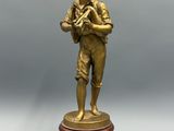 une figurine antique en bronze représentant un garçon tenant une batte de baseball