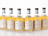 six bottles of whisky lined up in a row on a white surface