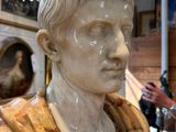 a marble bust of a man in a room with a chandelier in the background