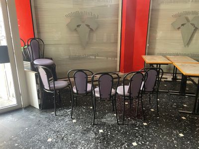 de nombreuses chaises et tables dans une pièce où est accrochée une horloge au mur