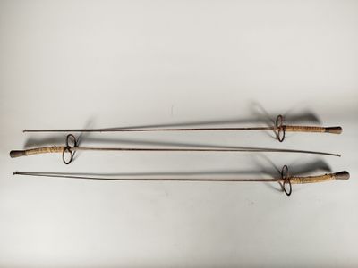 Trois cannes à pêche à l'ancienne sont accrochées au mur.