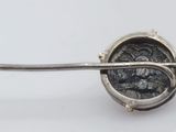 a silver spoon with a coin in it on a white surface