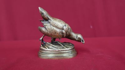 a bronze statue of a bird sitting on top of a table