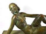 bronze statue of a woman laying on her stomach on a marble base