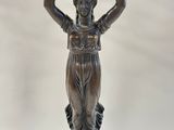 a bronze statue of a woman holding a basket on her head