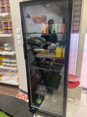 un réfrigérateur à porte vitrée dans un magasin rempli de produits alimentaires