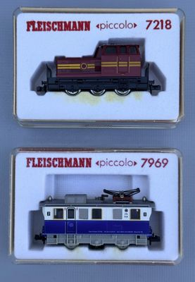 two miniature trains are displayed in a display case on a table