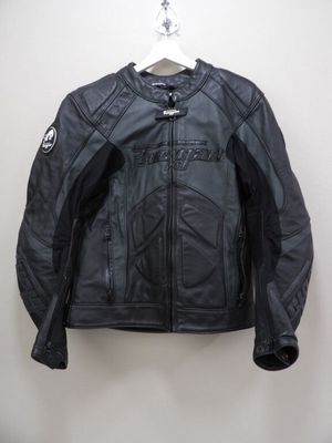 une veste de moto en cuir noir suspendue à un cintre accroché au mur