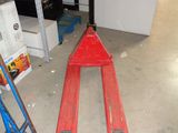 un chariot élévateur rouge garé au milieu du sol d'un entrepôt