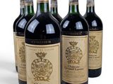 six bottles of wine are lined up in a row on a white surface